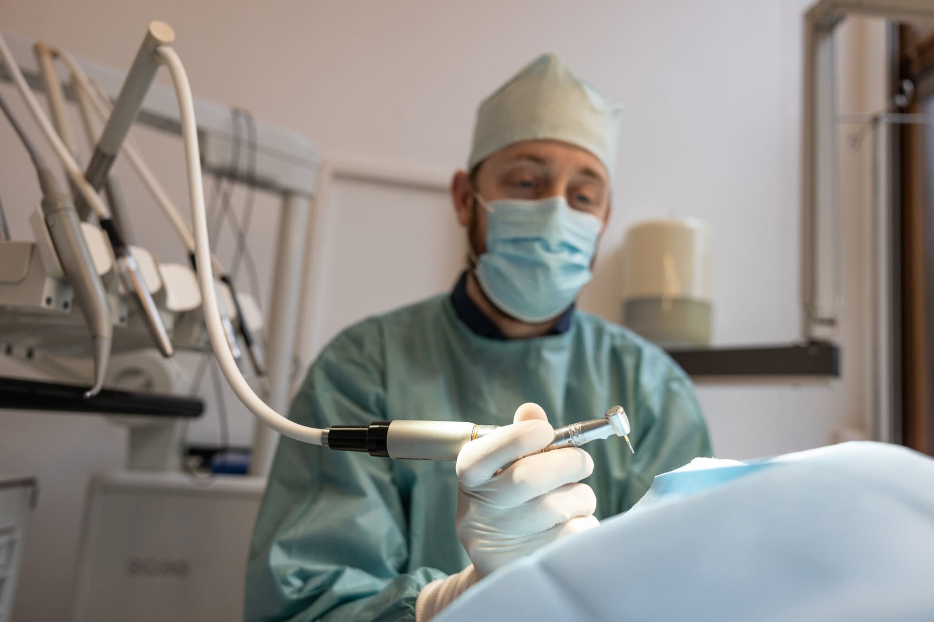 Een dierenarts in operatiekleding werkt met een tandheelkundig handstuk bij een dier onder narcose.